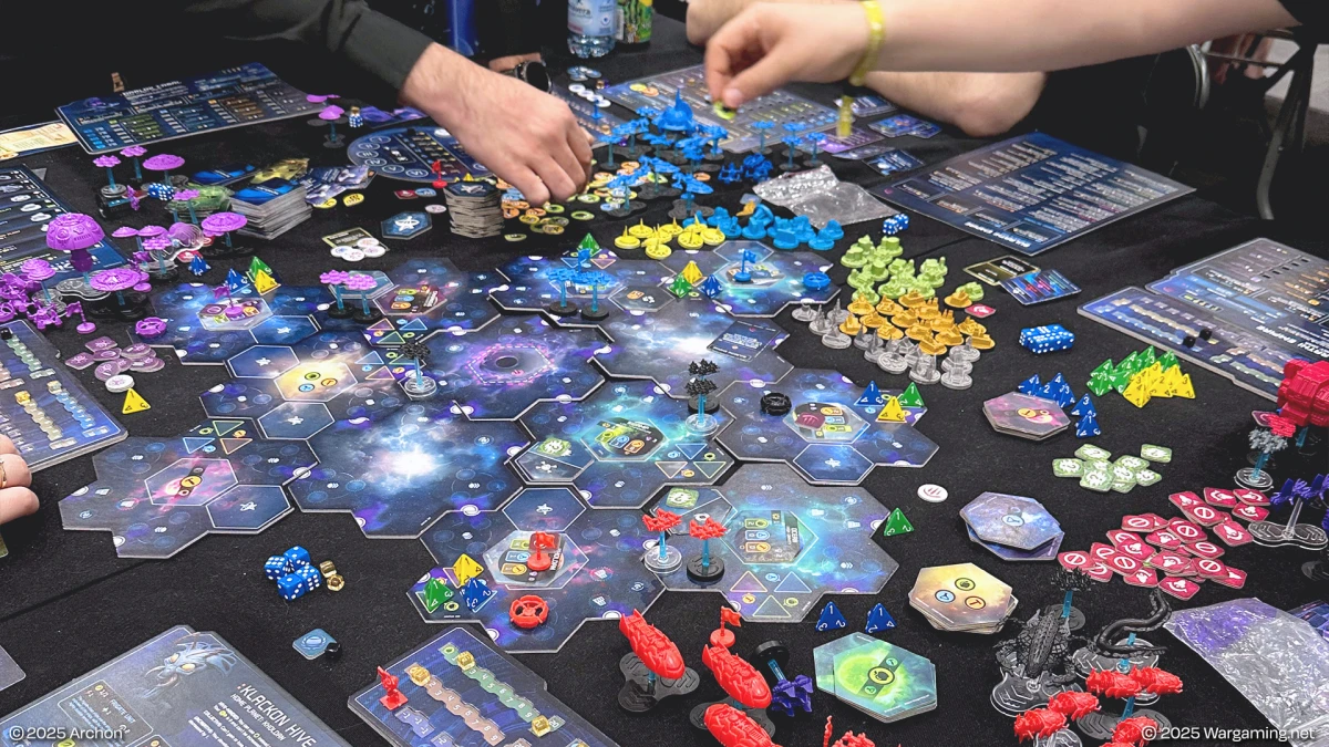 Players engaged in a complex space-themed board game with colorful tokens, hexagonal tiles, and player boards